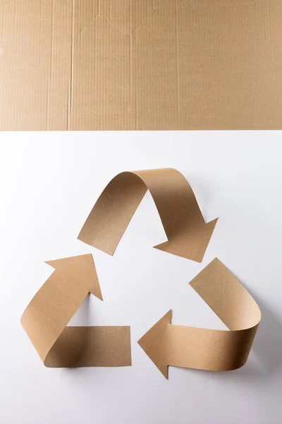 Close up of recycling symbol of paper arrows and carton on white background with copy space. Global ecology and recycling concept.