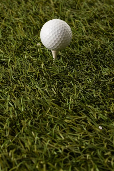 White golf ball on golf tee on grass with copy space. Golf, sports and competition concept.