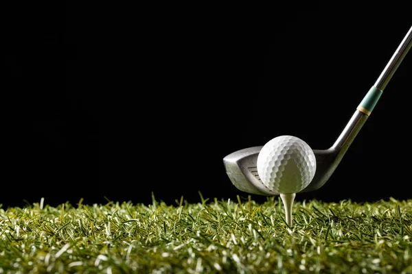 White golf ball on golf tee and golf club on grass with copy space. Golf, sports and competition concept.