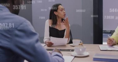 Animation of growing numbers over diverse female manager discussing reports with coworkers in office. Digital composite, multiple exposure, growth, teamwork, business and technology concept.