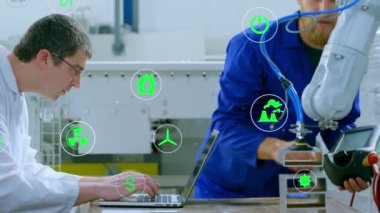 Animation of icon in circles over caucasian male engineers working on laptop and checking machine. Digital composite, multiple exposure, business, radioactive, recycle, teamwork and technology.