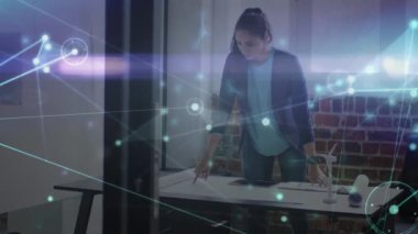 Animation of network of connections against indian woman working on a plan at office. Global networking and business technology concept