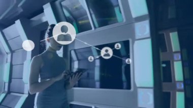 Animation of connected icons, caucasian woman walking in corridor of office and using digital tablet. 