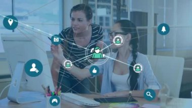 Animation of network of profile icons against two diverse female colleagues discussing at office. Global networking and business technology concept