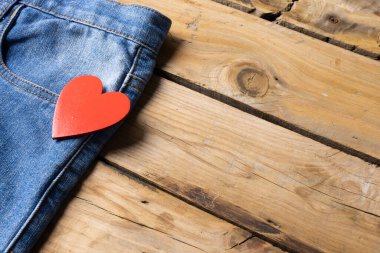 Jeans with heart lying on wooden surface. Clothes, fashion, design, fabrics, materials and shopping concept.
