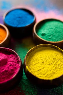 Close up of multi coloured powder in bowls and copy space on black background. Holi festival, colour, hindu tradition and celebration concept.