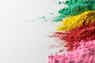 Close up of multi coloured powder and copy space on white background. Holi festival, colour, hindu tradition and celebration concept.