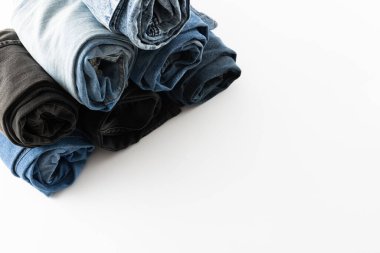 Diverse folded jeans lying in stack on white background. Clothes, fashion, design, fabrics, materials and shopping concept.