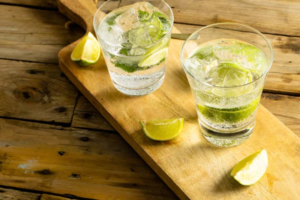 Glasses Water Limes Wooden Board Wooden Surface Drinks Cocktails Beverage — Stok fotoğraf