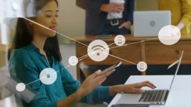 Animation of network of digital icons against biracial woman talking on smartphone at office. Global networking and business technology concept