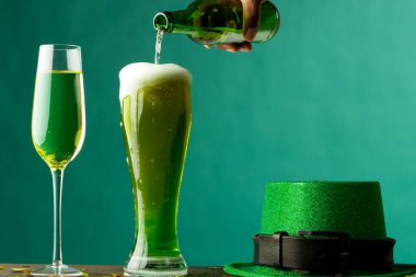 Image of beer and champagne glasses, green hat and copy space on green background. St patrick's day, irish tradition and celebration concept.