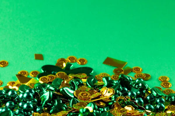 Image of green and gold jewellery and copy space on green background. St patrick's day, irish tradition and celebration concept.