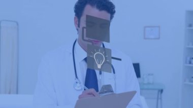 Animation of network of digital icons over caucasian male doctor writing on clipboard at hospital. Global networking and medical healthcare technology concept