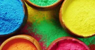 Video of close up of multi coloured powders in bowls with copy space on black background. Holi festival, hindu tradition and celebration concept