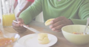 Animation of healthy text over african american man eating breakfast. Food, drink and lifestyle concept concept digitally generated video.