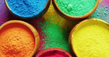 Video of close up of multi coloured powders in bowls with copy space on black background. Holi festival, hindu tradition and celebration concept