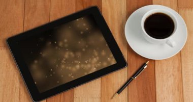 Animation of tablet with light trails on screen and cup of coffee on desk. Global technology, abstract background and digital interface concept digitally generated video.