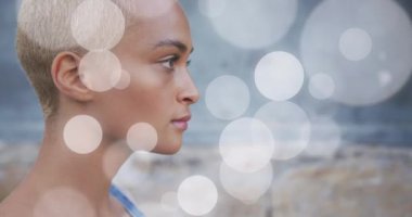 Animation of light spots over biracial woman smiling. Lifestyle, abstract background and digital interface concept concept digitally generated video.