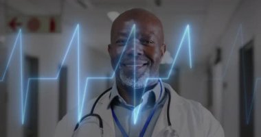 Animation of cardiograph over diverse doctors working at hospital. Medicine, healthcare and digital interface concept concept digitally generated video.