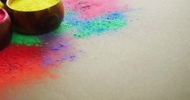 Video of multi coloured powders and bowls with copy space on black background. Holi festival, hindu tradition and celebration concept