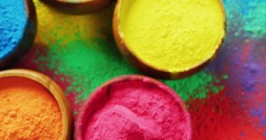 Video of close up of multi coloured powders in bowls with copy space on black background. Holi festival, hindu tradition and celebration concept