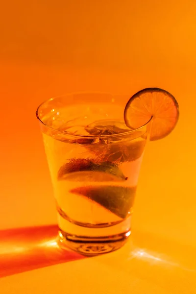 Glas Med Vatten Och Bitar Citron Med Kopieringsutrymme Över Orange — Stockfoto