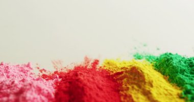 Video of multi coloured powders with copy space on white background. Holi festival, hindu tradition and celebration concept