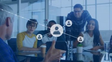 Animation of connected profile icons over diverse man showing cellphone and explaining to coworkers. Digital composite, multiple exposure, communication, teamwork, planning and technology concept.