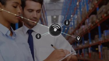 Animation of network of icons over caucasian male and female supervisors discussing at warehouse. Global networking and transportation business technology concept