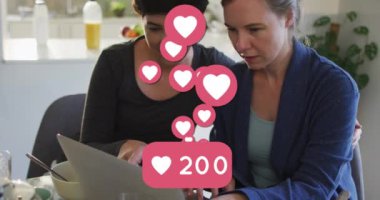 Animation of heart emojis and numbers over happy caucasian female couple in love. Love, romance and celebration concept digitally generated video.