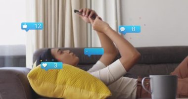 Animation of social media icons and numbers over biracial woman using smartphone. Global social media and data processing concept digitally generated video.