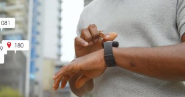 Animation of social media icons floating over mid section of a man using smartwatch outdoors. Social media networking technology concept
