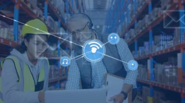 Animation of network of icons over diverse male supervisor and female worker discussing at warehouse. Global networking and logistics business technology concept.