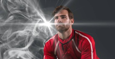 Caucasian male athlete against smoke effect and light spot on grey background. sports tournament and competition concept