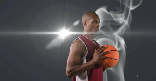 Африканский Американский Баскетболист Держит Мяч Против Дыма Светлого Пятна Сером — стоковое фото