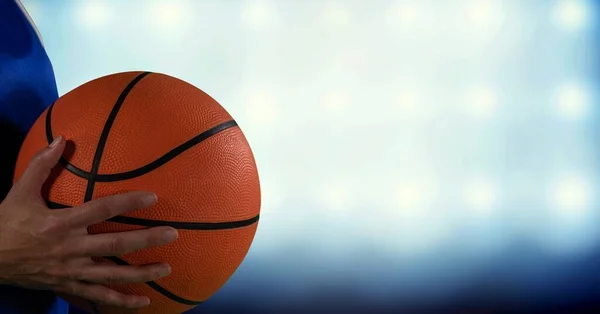 Composition of midsection of female basketball player with ball, spotlights and copy space. sport and competition concept digitally generated image.