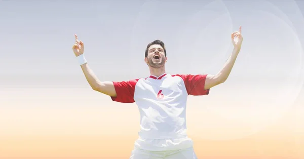 Composition of smiling caucasian male football player with arms in air celebrating victory. sport, fitness and active lifestyle concept digitally generated image.