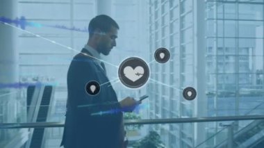 Animation of network of connections with icons over biracial businessman using talking on smartphone. Global business, connections and digital interface concept digitally generated video.