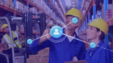 Animation of network of icons over caucasian male and female worker checking stock at warehouse. Global networking and logistics business technology concept