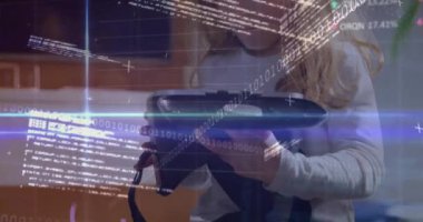 Animation of binary codes, computer language, trading board over caucasian girl holding vr headsets. Digital composite, multiple exposure, stock market, coding, machine learning and technology.
