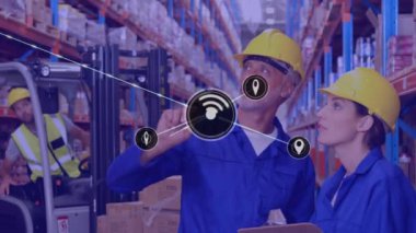 Animation of network of icons over caucasian male and female worker checking stock at warehouse. Global networking and logistics business technology concept