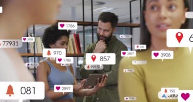 Bildirim simgelerinin animasyonu ve dijital tablet üzerinde plan yapan çeşitli iş arkadaşlarının sayısı. Dijital bileşik, çoklu pozlama, ofis, takım çalışması, sosyal medya ve teknoloji kavramı.