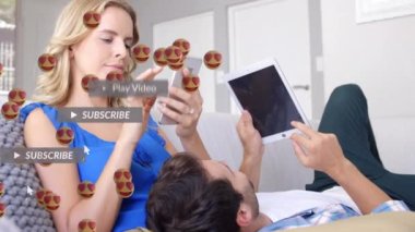 Kalp gözleri animasyonu, evdeki elektronik cihazları kullanarak beyaz bir çiftin üzerinde yüzen emojilerle karşılaşıyor. Sosyal medya ağı ve iş teknolojisi kavramı