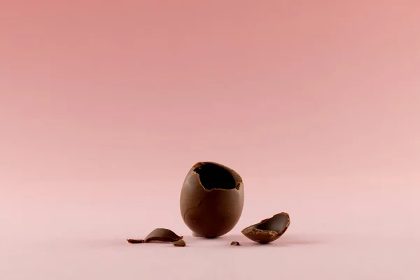 Image of broken chocolate easter egg and copy space on pink background. Easter, religion, tradition and celebration concept.