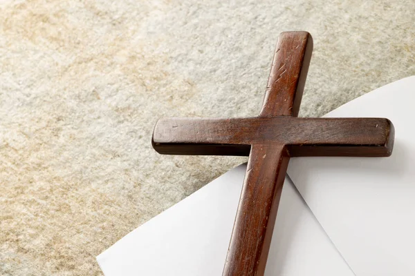 Image of close up of cross with notebook and copy space on stone background. Easter, religion, tradition and celebration concept.