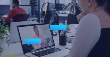 Ofiste dizüstü bilgisayarda beyaz bir kadının görüntülü konuşma yapması üzerine mesaj simgelerinin canlandırılması. Sosyal medya ağı ve iş teknolojisi kavramı