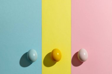 Sarı, pembe ve mavi paskalya yumurtaları ve sarı, pembe ve mavi arka planda kopya alanı. Paskalya, din, gelenek ve kutlama kavramı.