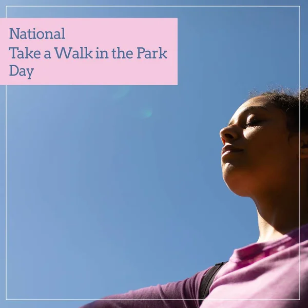 National take a walk in the park day text over biracial woman practicing yoga in park. National take a walk in the park day and celebration concept digitally generated image.