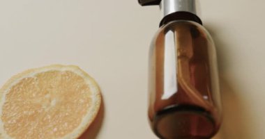 Pompalı cam şişeyi, limon dilimini ve bej arka planda kopyalama alanını kapat. Plastiksiz güzellik ve ekolojik ambalaj kavramı.