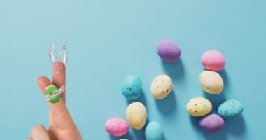 Paskalya süsleri ve mavi arka planda paskalya yumurtaları olan el animasyonu. Paskalya, gelenek ve kutlama konsepti dijital olarak oluşturuldu.